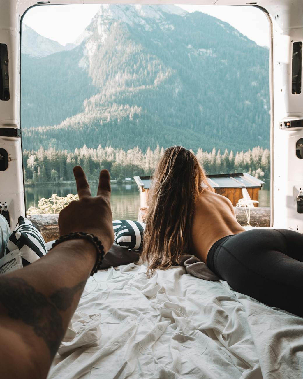 woman in black tank top and black pants lying on white bed